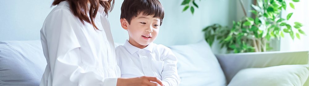 Mother and child sitting on the sofa and looking at the screen of the tablet PC